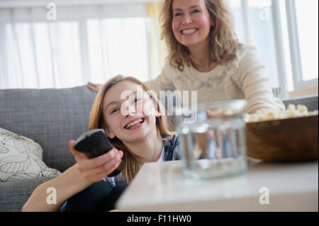 Caucasian mother and daughter watching television on sofa Banque D'Images