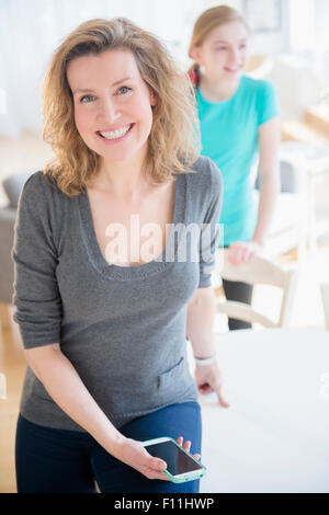 Caucasian woman holding cell phone in dining room Banque D'Images