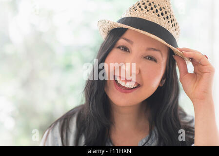 Smiling mixed race woman wearing straw hat Banque D'Images