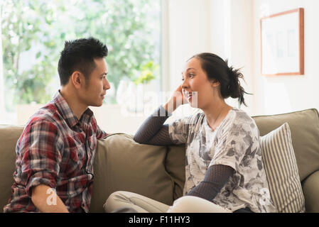 Couple talking on sofa in living room Banque D'Images