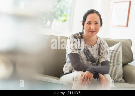 Mixed Race woman sitting on sofa in living room Banque D'Images