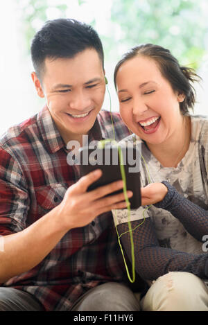 Laughing couple watching digital tablet on sofa Banque D'Images