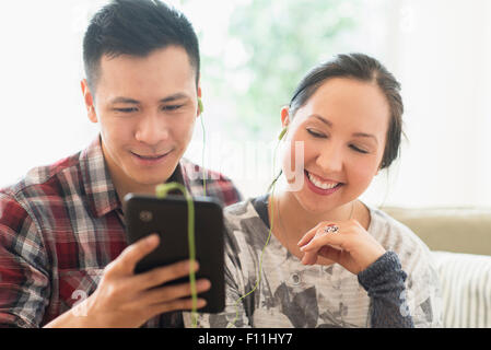 Laughing couple watching digital tablet on sofa Banque D'Images