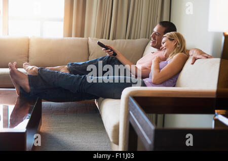 Couple watching television on sofa Banque D'Images