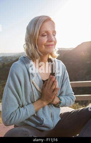 Caucasian woman meditating on hilltop Banque D'Images