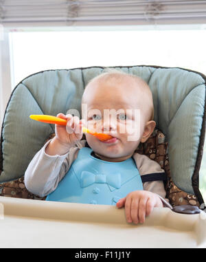 Caucasian baby boy eating dans une chaise haute Banque D'Images