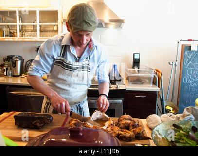 Man carving viande rôtie dans la cuisine Banque D'Images