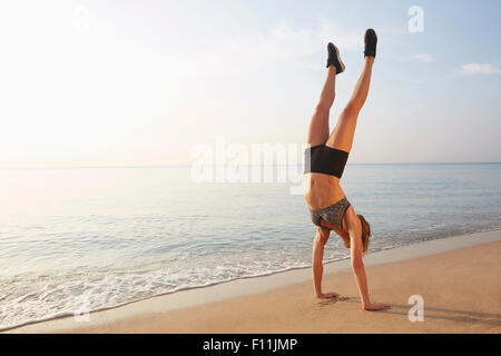 Athlète doing handstand on beach Banque D'Images