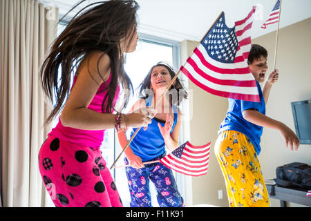 Les enfants hispaniques sautant avec American flags Banque D'Images