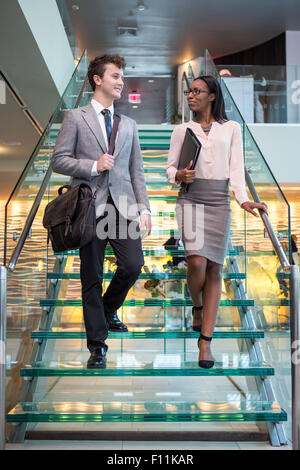 Business people talking on staircase in office Banque D'Images