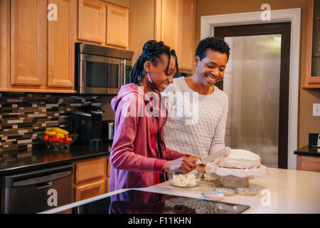 Black mother and daughter decorating cake in kitchen Banque D'Images