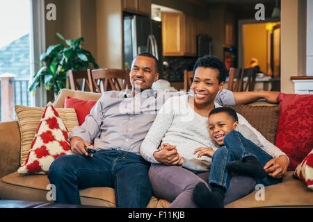 La famille noire à regarder la télévision sur le canapé Banque D'Images