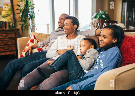 La famille noire à regarder la télévision sur le canapé Banque D'Images