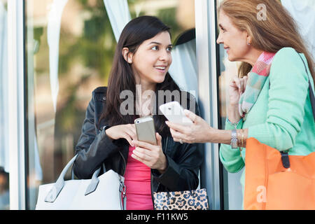 Mère et fille à l'aide de téléphones mobiles à l'extérieur Banque D'Images