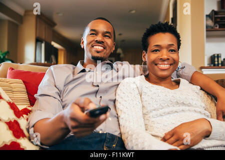 Black couple watching television on sofa Banque D'Images