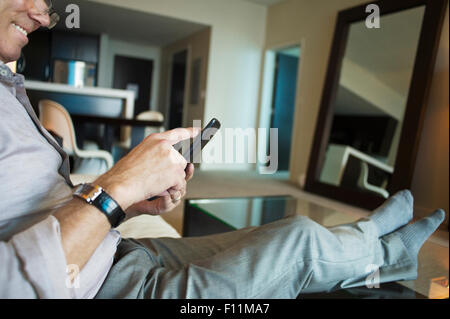 Caucasian businessman using cell phone in hotel room Banque D'Images