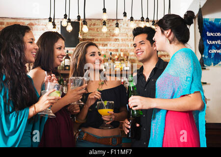 Amis hispaniques ayant verre au bar Banque D'Images