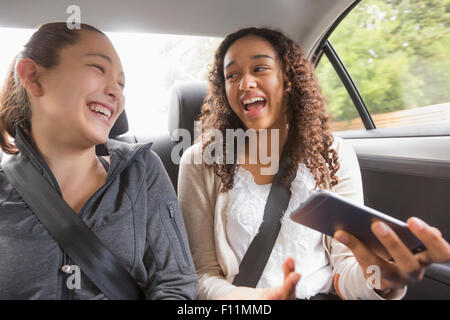 Teenage Girls using cell phone in car siège arrière Banque D'Images