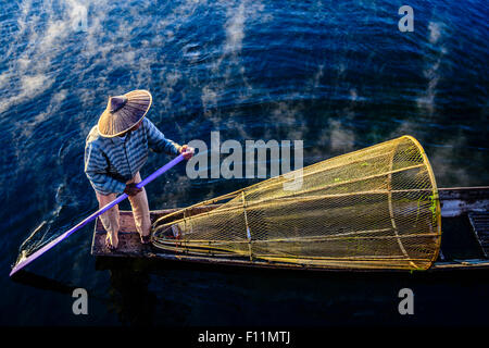 High angle view of Asian fisherman à l'aide de filet de pêche en canoë sur la rivière Banque D'Images