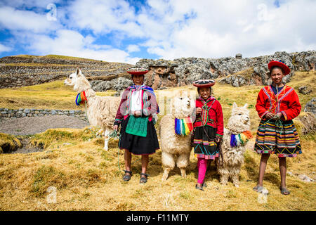 La mère et les enfants hispaniques debout avec des lamas in rural landscape Banque D'Images