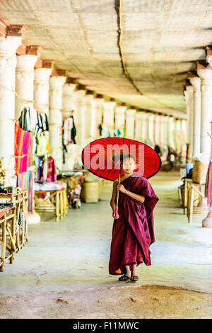 Moine asiatique en formation avec parasol walking in hallway Banque D'Images