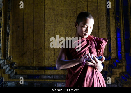 Moine asiatique en formation using cell phone in temple Banque D'Images