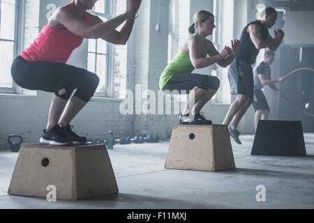 Les athlètes accroupi sur plates-formes dans une salle de sport Banque D'Images