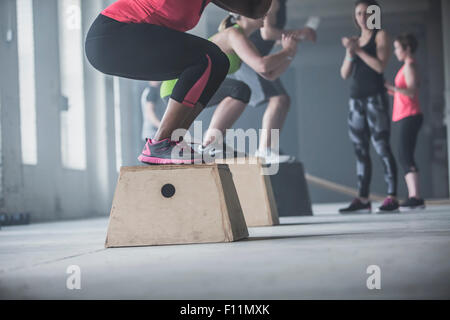 Les athlètes accroupi sur plates-formes dans une salle de sport Banque D'Images