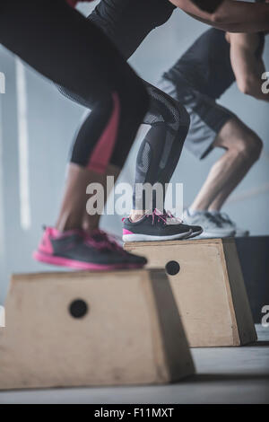 Les athlètes sautant sur plates-formes dans une salle de sport Banque D'Images