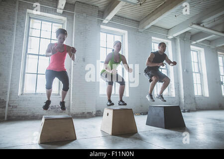 Les athlètes sautant sur plates-formes dans une salle de sport Banque D'Images