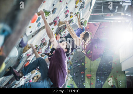 Les athlètes climbing rock wall in gym Banque D'Images