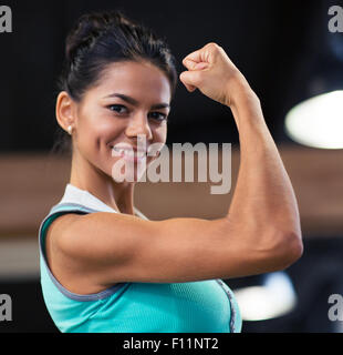Smiling belle femme montrant ses biceps in gym Banque D'Images