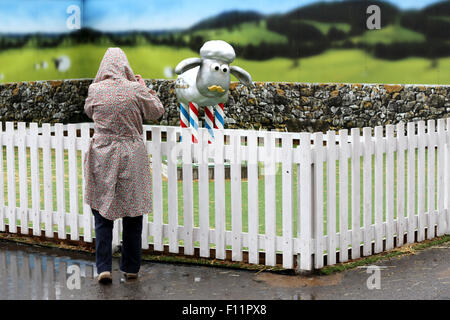 Sans se laisser décourager par la pluie un visiteur prend une photo, avec son téléphone, d'un caractère Shaun le mouton. Bristol Shaun dans la ville sentier de chèvres 2015 Banque D'Images