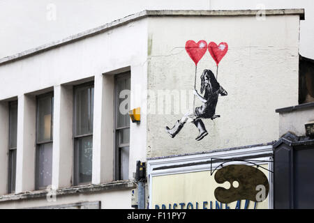 Street art, style Banksy, à Park Row Bristol.L'image montre une fille sur une question qui est suspendue par deux ballons de forme de coeur.L'artiste est jps Banque D'Images