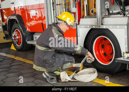 Tout en tenant accroupi pompier camion par flexible Banque D'Images