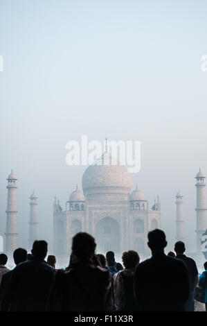 Agra, Uttar Pradesh, Inde. Taj Mahal dans la brume à l'aube, les touristes en silhouette. Banque D'Images