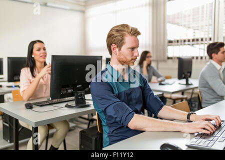 Young handsome student using computer in classroom Banque D'Images