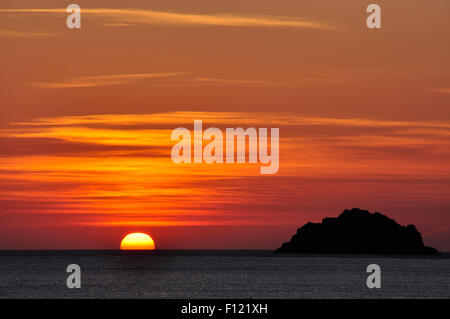 Cornouailles du nord - orange coucher de soleil sur la mer Noire - rouge et or - un ciel strié off shore dans l'île de silhouette sombre Banque D'Images