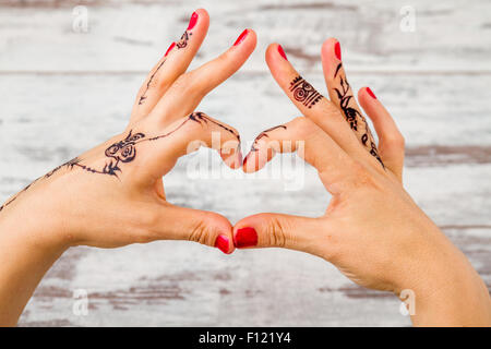 Femme les mains avec du vernis à ongles peint avec henné noir faisant le geste du cœur Banque D'Images