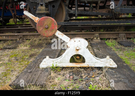 Vieux train de chemin de fer exploitée manuellement le levier des points de trace, un train derrière elle. Banque D'Images