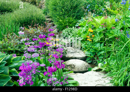 Marches de pierre en passant par l'anglais charmant chalet jardin plein d'eau des fleurs et arbustes Banque D'Images