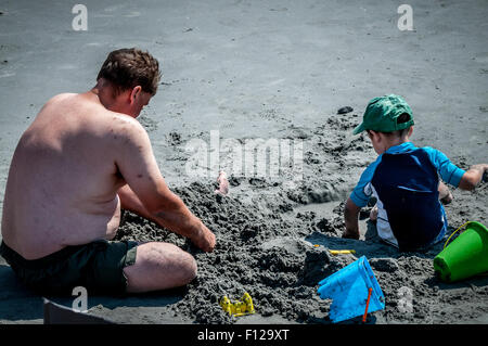 Jouer MATES,ce papa prend timeout de ses vacances pour faire quelques mouvements de terre avec son petit garçon, ou tout simplement jouer dans le sable. Banque D'Images