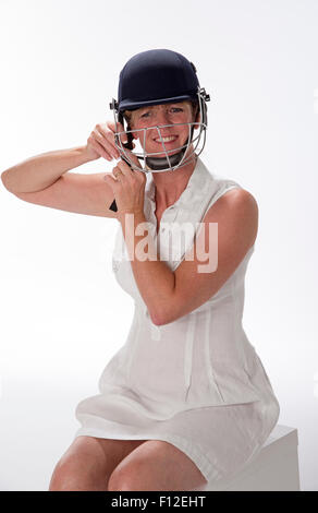 Portrait d'une femme cricketer ajustant son casque de sécurité Banque D'Images