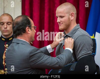 Paris, France. Août 24, 2015. Le Président français François Hollande, épingle la Légion d'honneur le pilote américain 1ère classe Spencer Stone lors d'une cérémonie à l'Elysée le 24 août 2015 à Paris, France. Avec ses amis Pierre Aleksander Skarlatos, Anthony Sadler et homme d'affaires britannique Chris Norman déjoué un attentat terroriste contre un train français. Banque D'Images