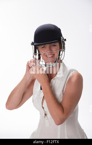 Portrait d'une femme cricketer ajustant son casque de sécurité Banque D'Images