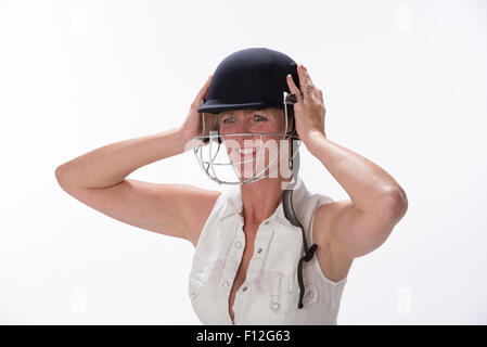 Portrait d'une femme cricketer ajustant son casque de sécurité Banque D'Images