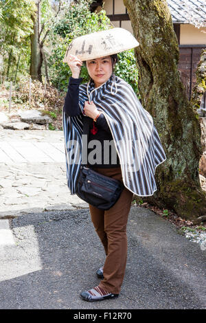 Magome, au Japon. La route Nakasendo, Japanese woman posing tout en portant un chapeau et la robe de voyage traditionnels autour des épaules. Eye-contact. Banque D'Images