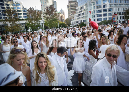 Vancouver, Canada. Août 25, 2015. Des gens habillés en blanc assister à la salle à manger en blanc à la Place du Canada, à Vancouver, Canada, le 25 août, 2015. Environ 4 500 personnes ont participé à l'événement à Vancouver pour profiter d'un dîner en plein air spécial. Diner en Blanc est une sorte de flash mob événement. Les participants sont nécessaires pour porter en blanc et se rassembler dans un lieu secret n'étant pas annoncé jusqu'à deux heures avant le début de la manifestation. Le Diner En blanc a eu lieu en France en 1988 pour la première fois et maintenant a eu lieu dans plus de 60 villes à travers le monde. Credit : Liang Sen/Xinhua/Alamy Live News Banque D'Images