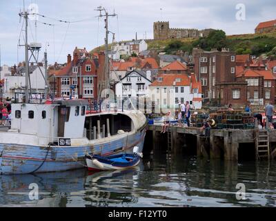 Bateaux de pêche dans le port de Whitby assis avec une église et maisons en arrière-plan. Banque D'Images