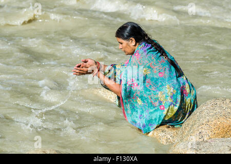 Un pèlerin femelle sur les rives du Gange est prier, offrant l'eau sainte, Gangotri, Uttarakhand, Inde Banque D'Images